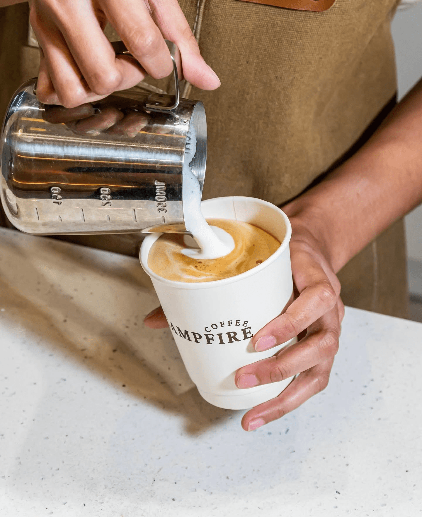Campfire Coffee barista pouring steamed milk into a cup