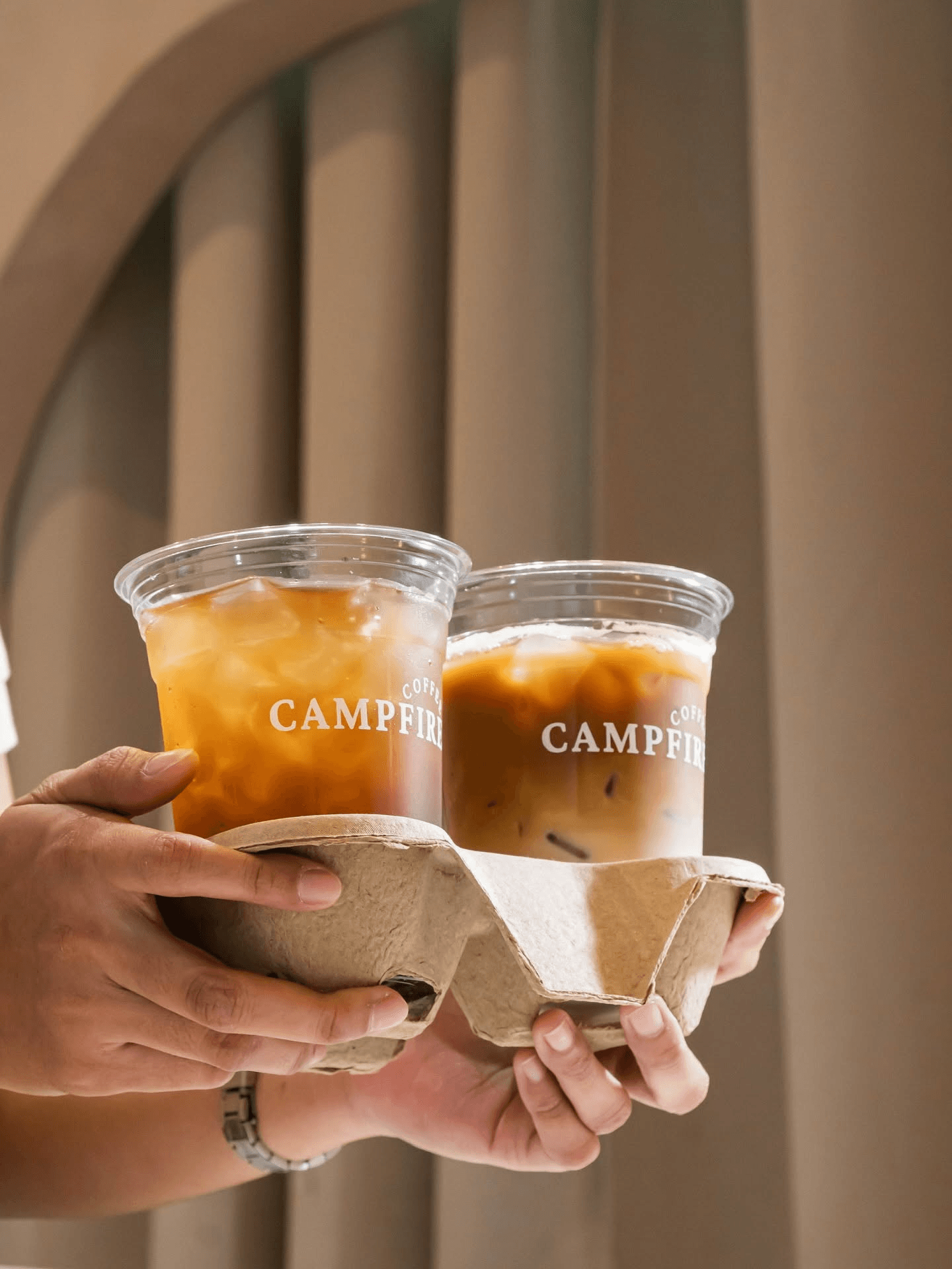 Two Campfire Coffee drinks being carried together